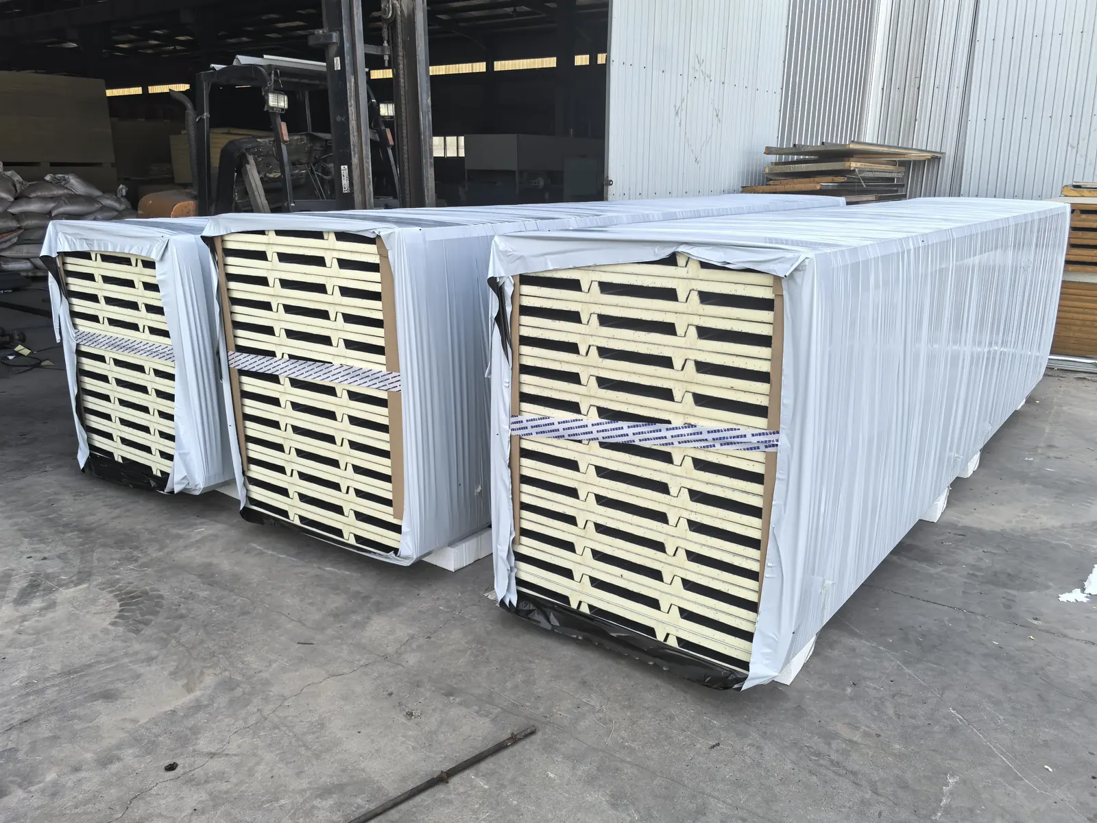 Export-packed insulated panel bundles strapped and wrapped for overseas shipping