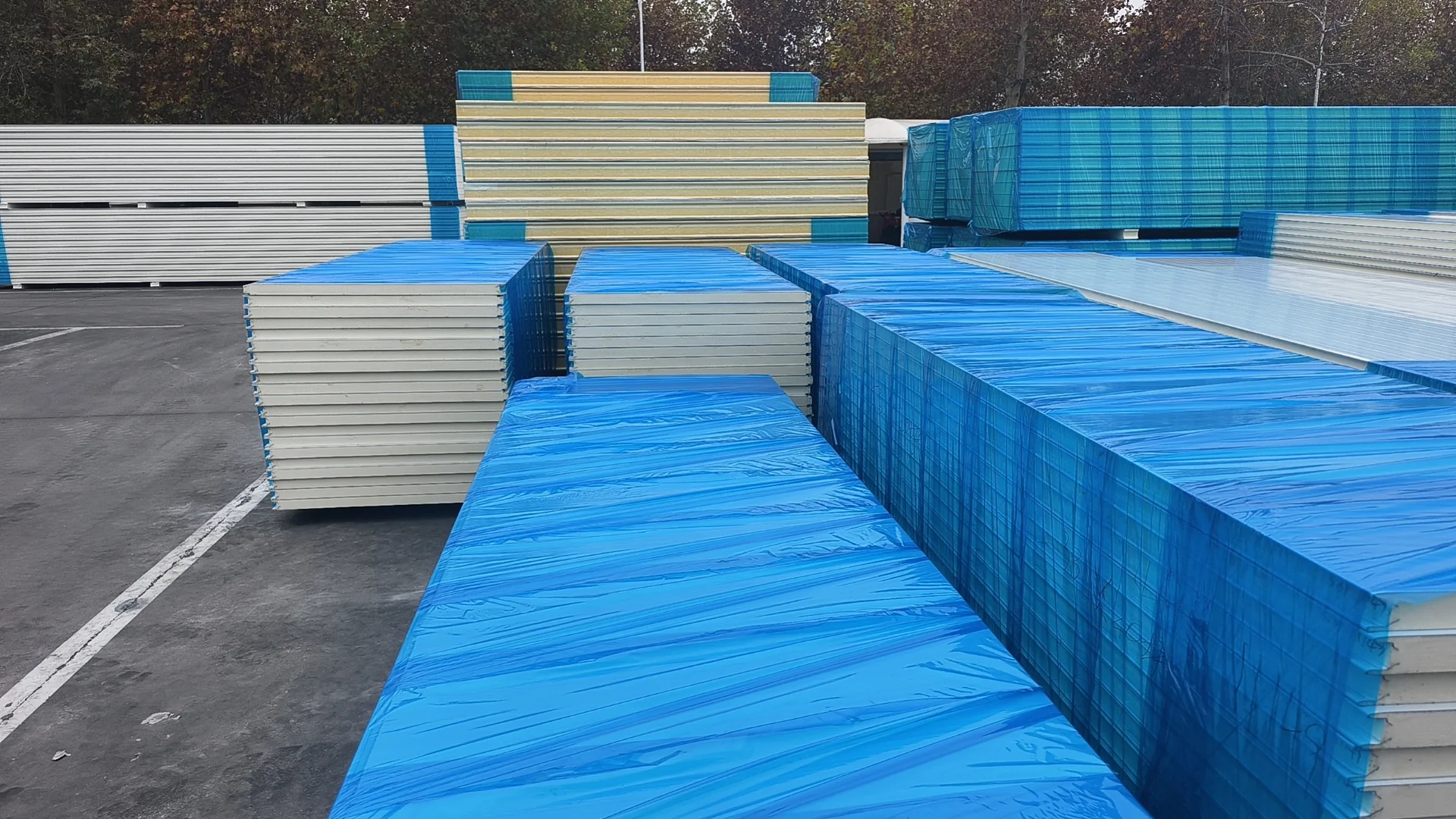 Multiple insulated sandwich panel bundles with protective blue wrap prepared for export
